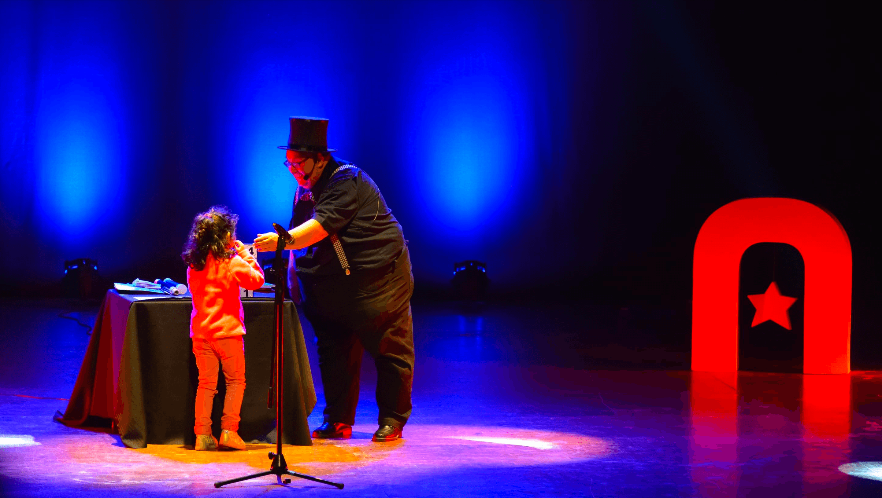 Artista de Atacamagica Kusiy comparte un número de ilusionismo con una niña en el escenario
