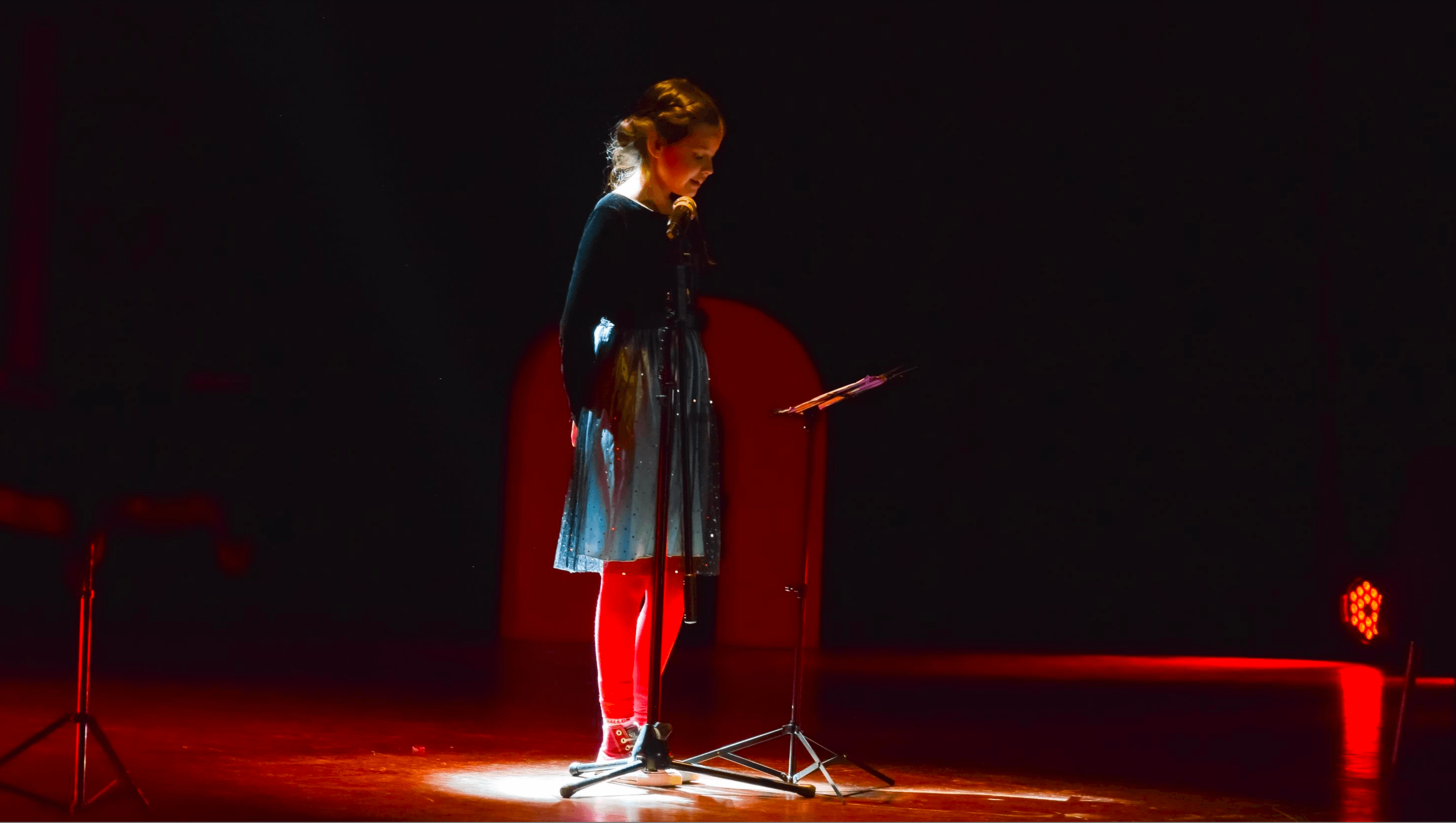 Niña participa frente al micrófono durante una función de Atacamagica Kusiy