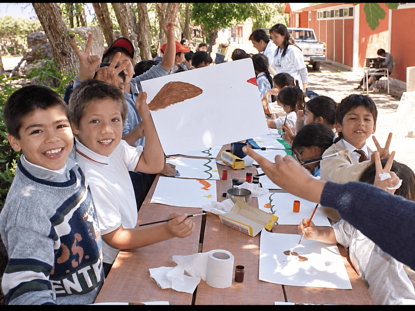 Niñas y niños muestran sus pinturas durante un taller de Maleta de payaso